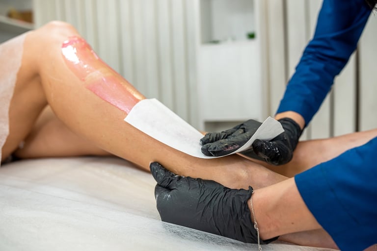 Female client legs applying pasta for depilation procedure of removal unwanted hair in spa, polymer waxing