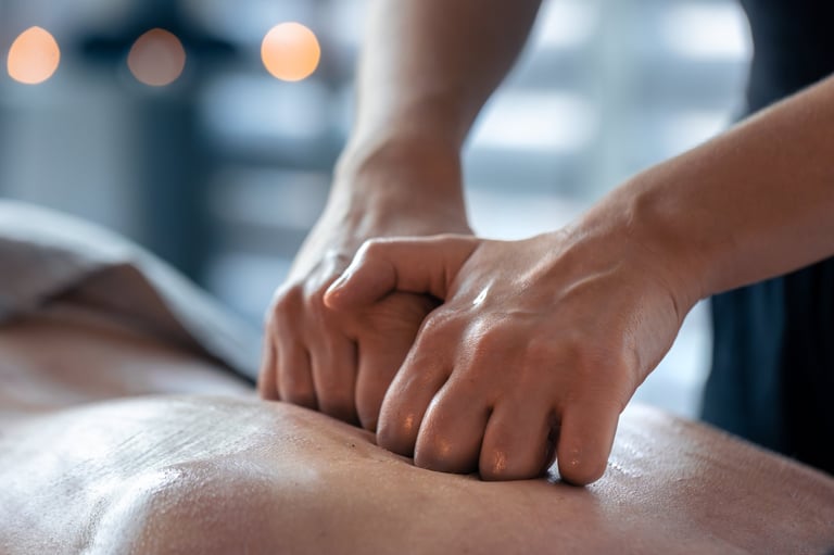 Two clenched hands press evenly on an oiled back
