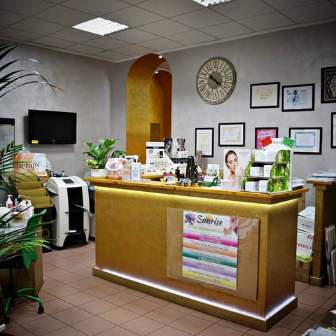 Modern reception desk with gold and white finishes in a beauty salon interior with artwork on walls and potted plants